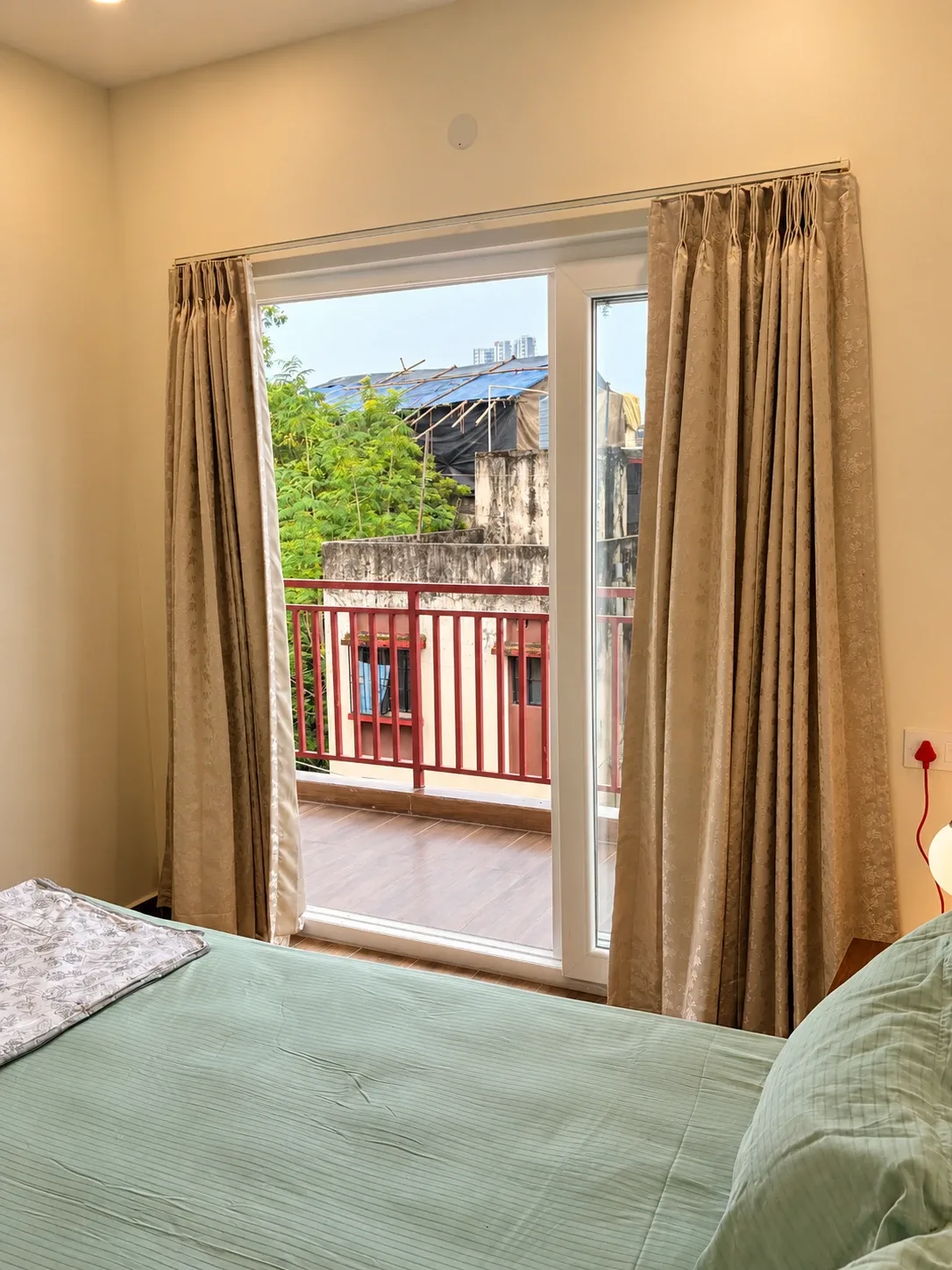 A bedroom at the Solitude Residency with a green bedspread, opening onto its own balcony